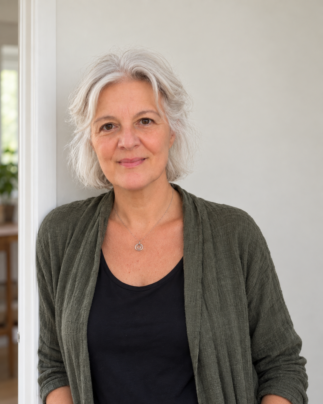 Gáborjáni Réka természetes portréja, olívazöld felsőben, világos háttér előtt